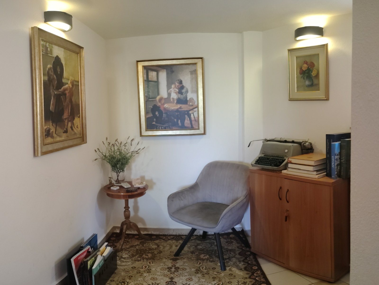 Ο χώρος αναμονής του Care Loft: πολυθρόνα, βοηθητικό τραπέζι με λουλούδια, βιβλία και πίνακες στους τοίχους